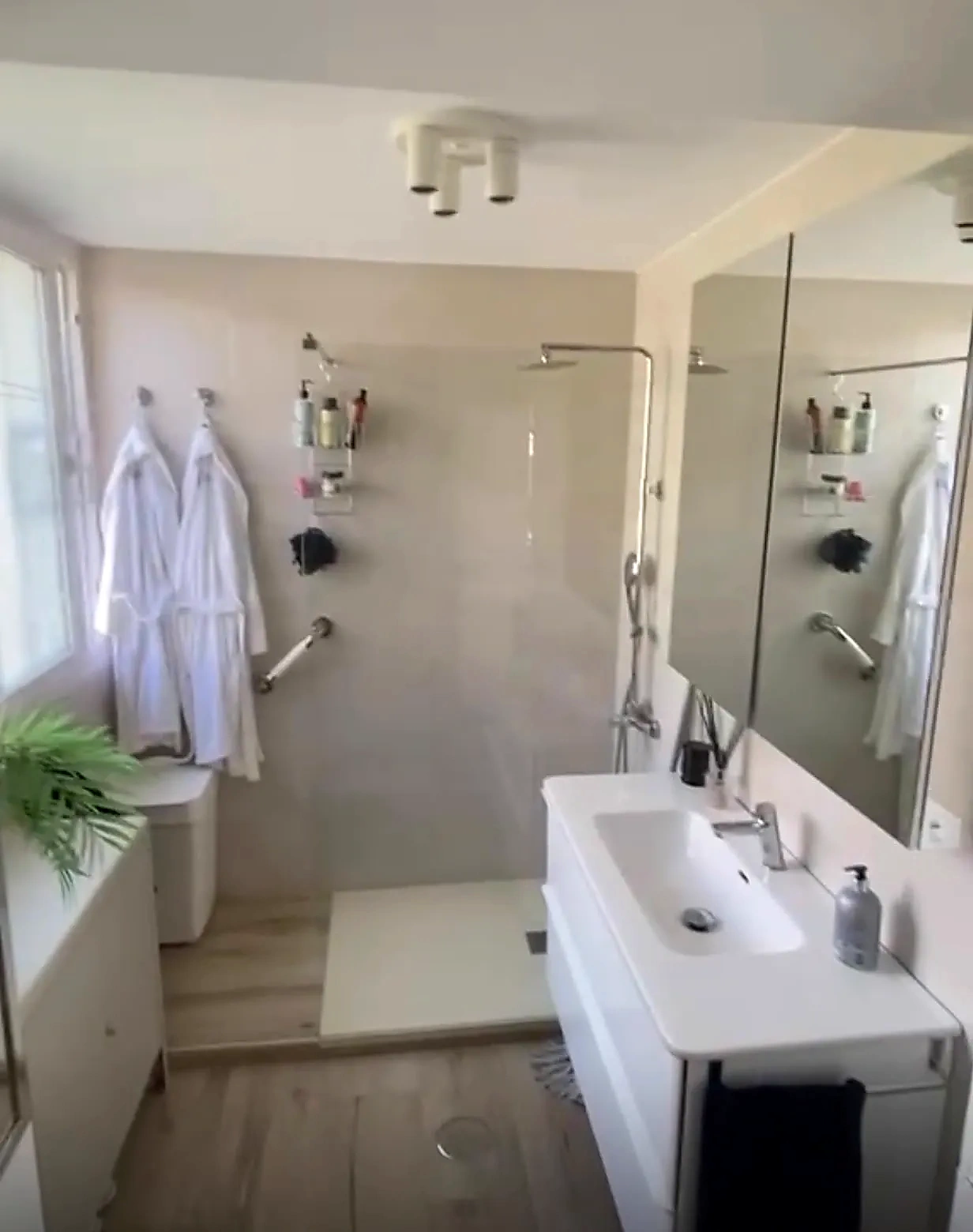 Baño en suite con ducha de obra a ras de suelo, mueble suspendido y luz natural