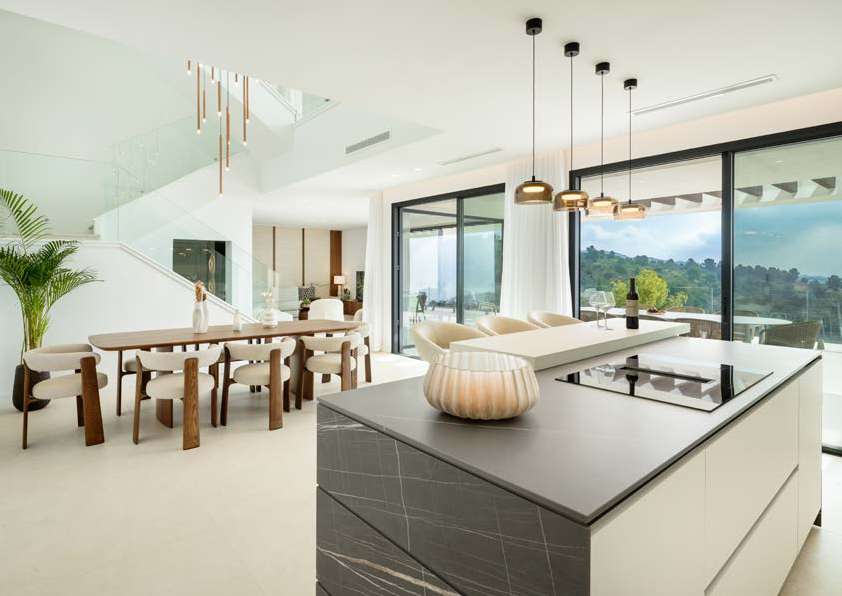 Cocina de líneas blancas abierta al comedor y a las vistas