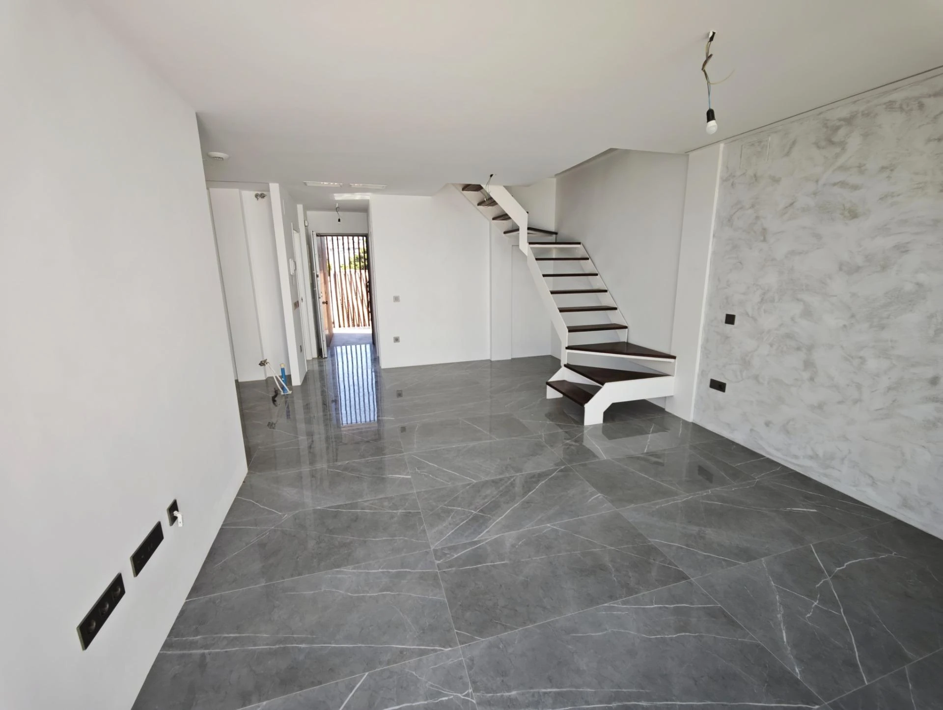 Salón diáfano con escalera escultórica hacia la planta superior