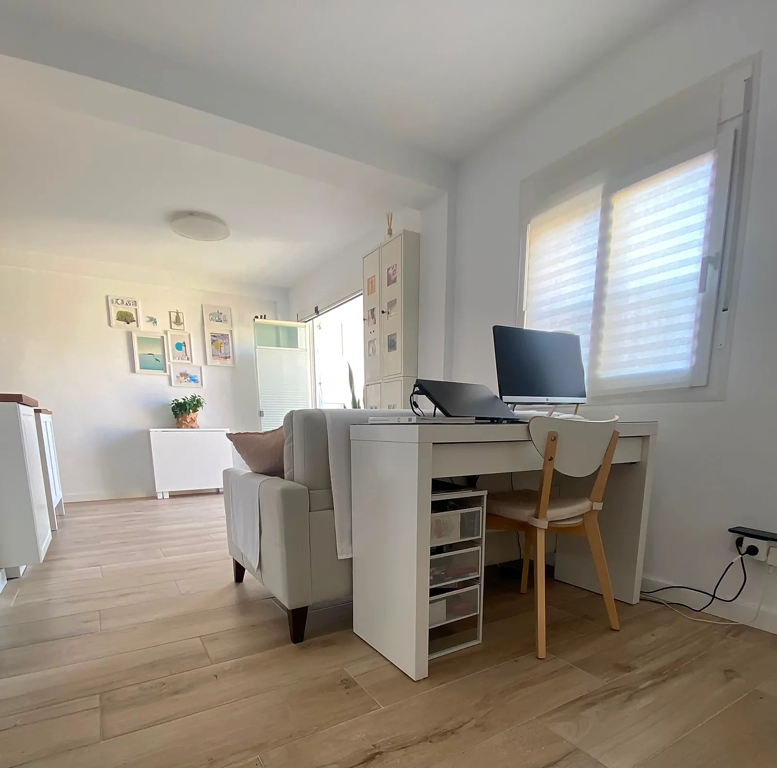 Zona de estudio junto a la ventana con escritorio y butaca, abierta al salón