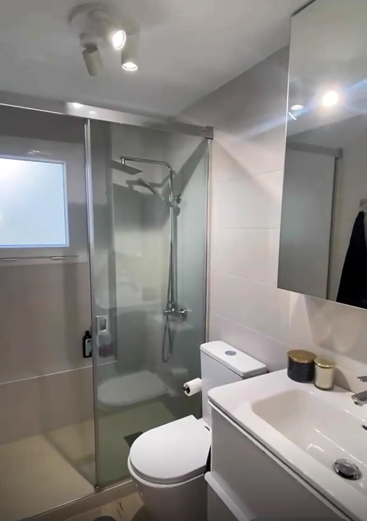 Segundo baño completo con ducha, mampara de cristal y ventilación natural