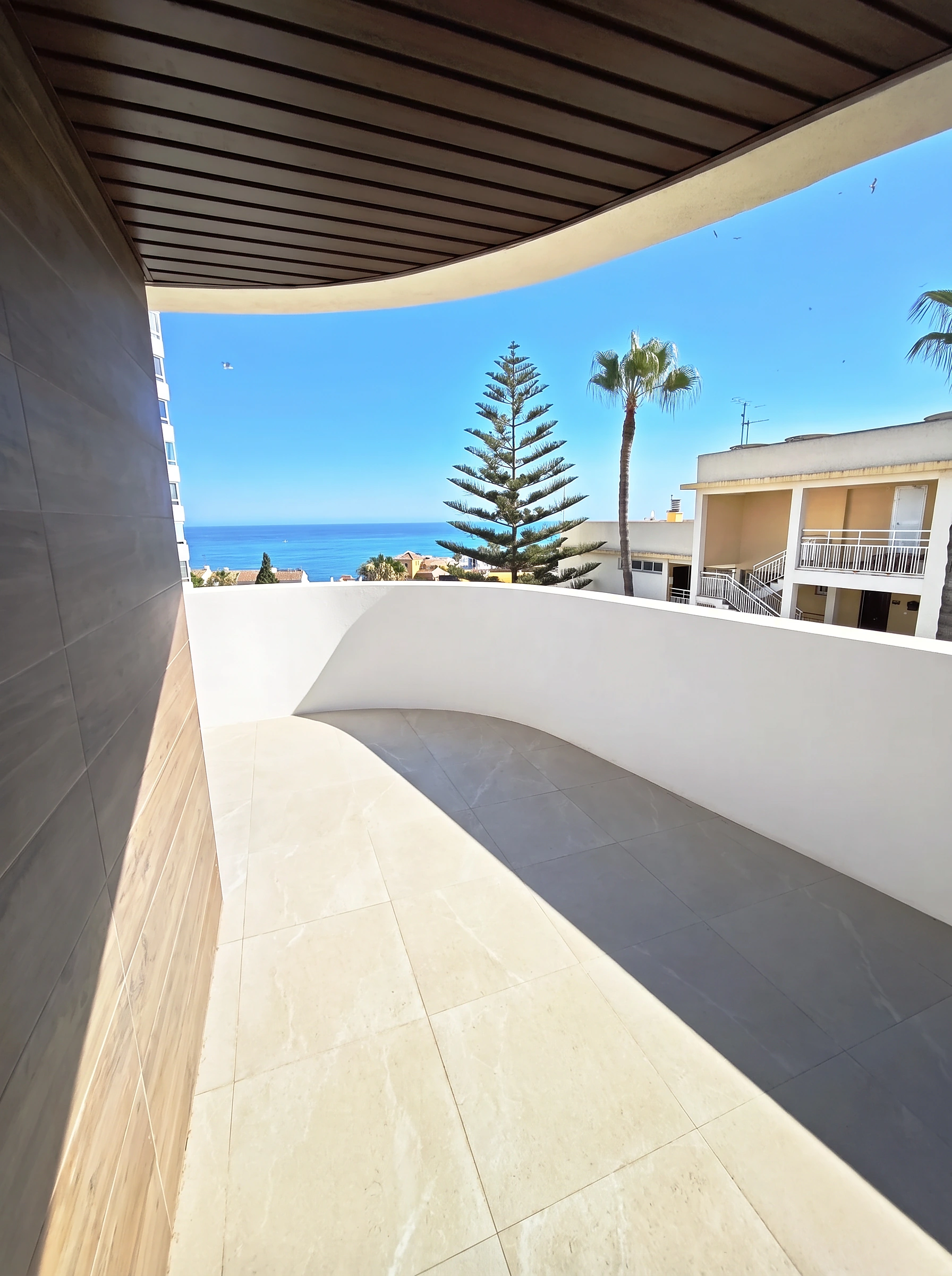 Terraza del ático con palmeras y el Mediterráneo al fondo en Benalmádena