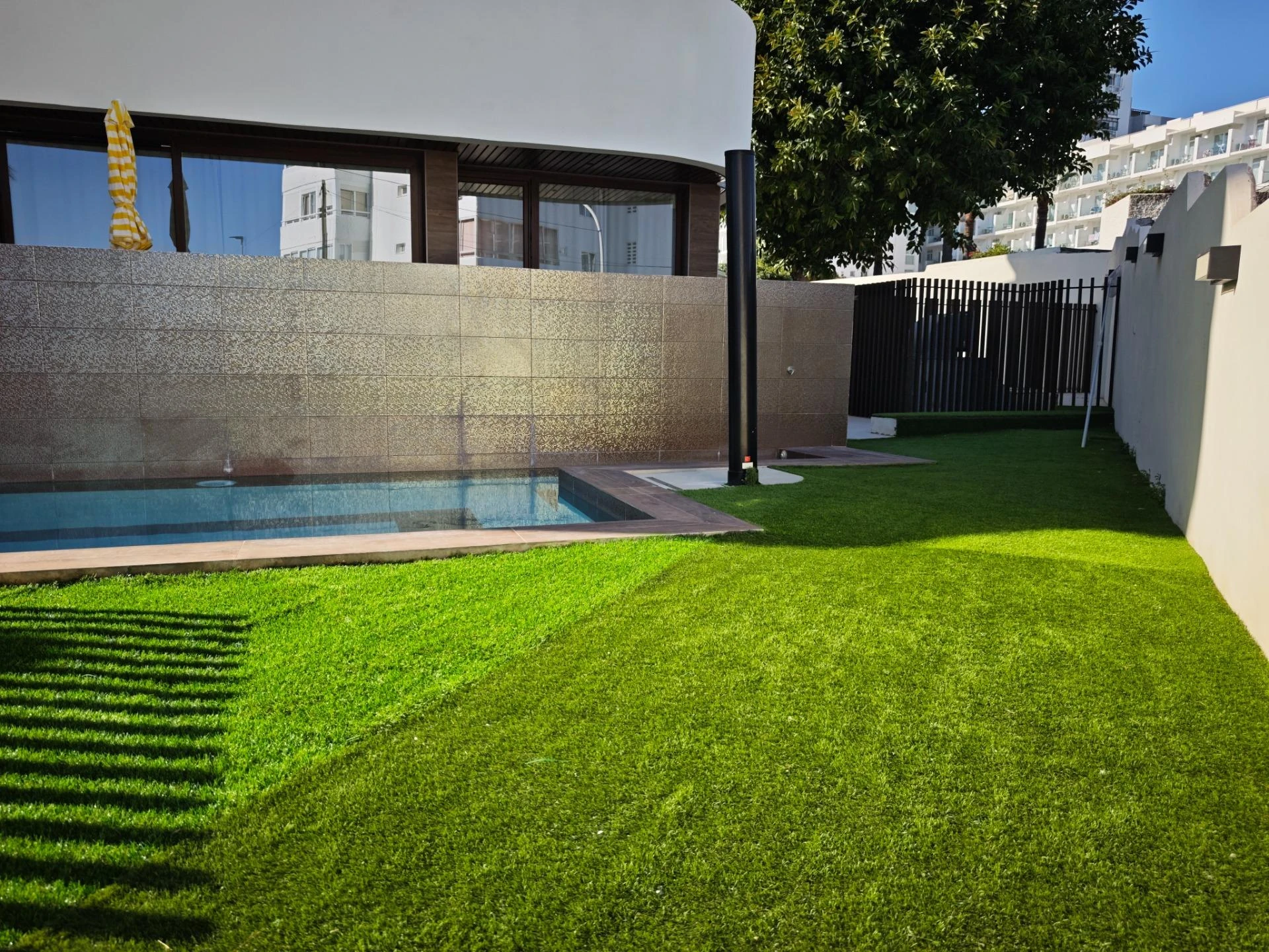 Jardín comunitario con césped y piscina del edificio