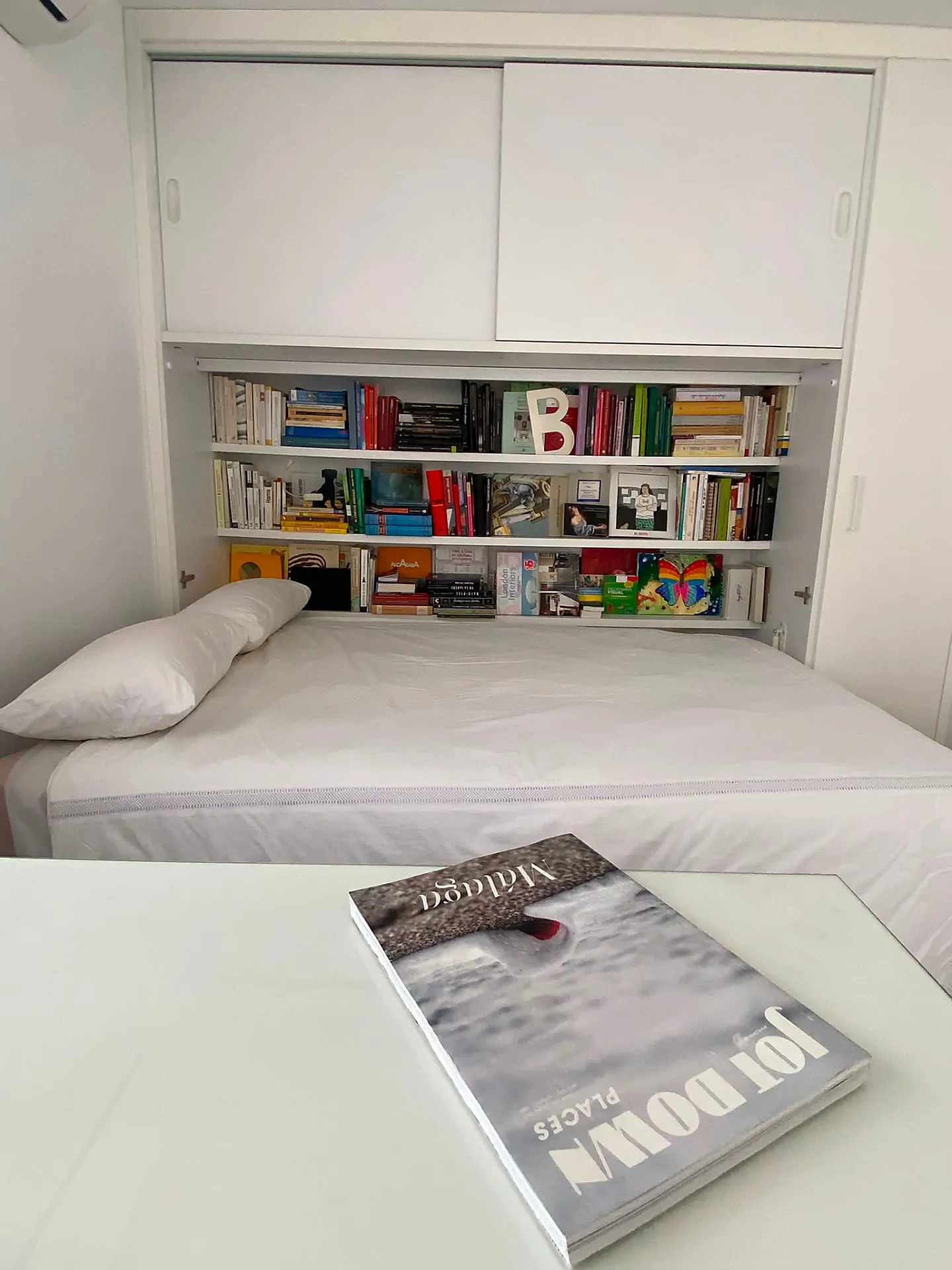 Cama extraíble desplegada bajo la estantería de obra con libros