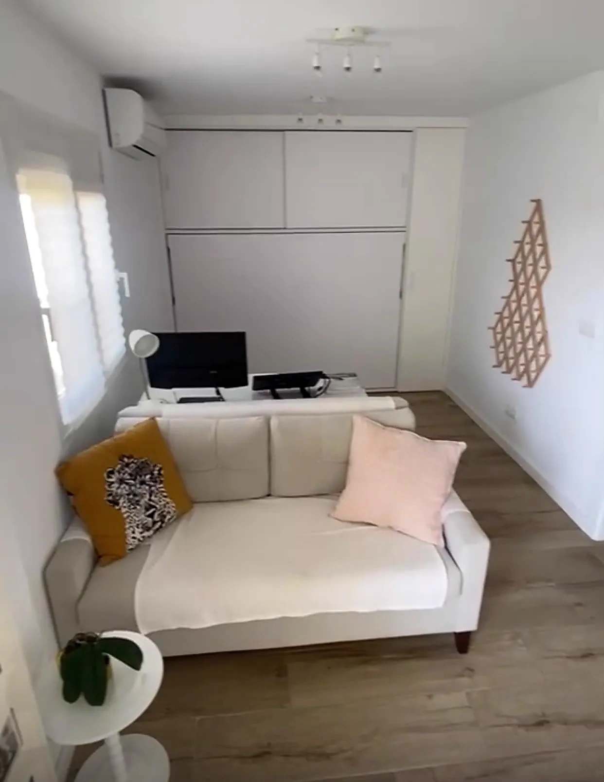 Estudio con sofá y frente de armarios que oculta la cama abatible