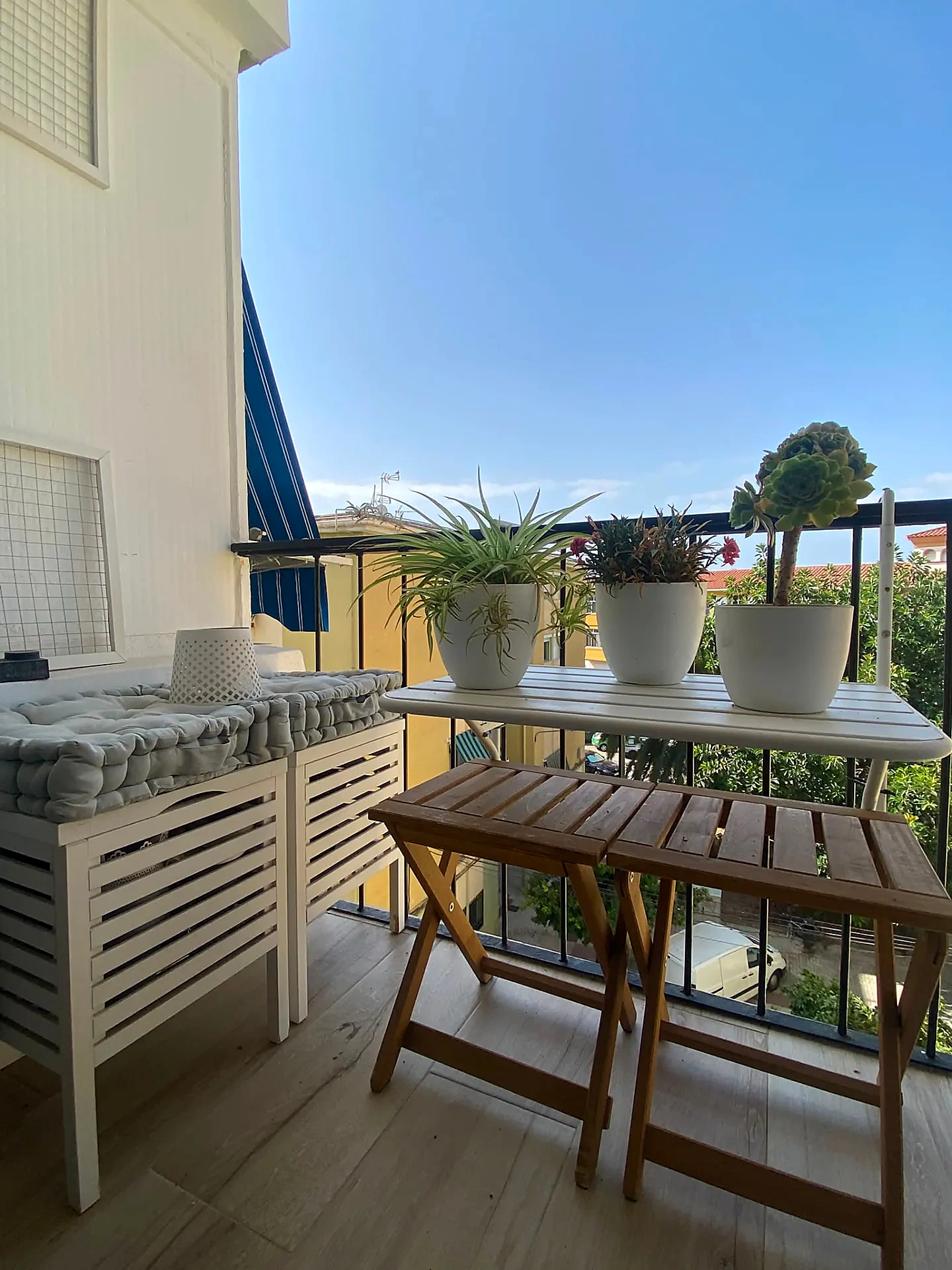 Terraza con mesa plegable, banco con almacenaje y plantas bajo el cielo de Málaga